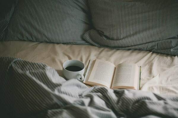Open book on a bed with warm evening light